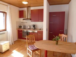 特格尔恩海姆特格尔恩海姆公寓的厨房配有红色橱柜和木桌