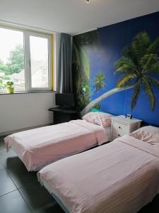 豪滕Rooms for longer stays with Invoice的棕榈树壁画客房的两张床