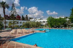 哈马马特Le Hammamet Hotel & SPA的一座带椅子的大型游泳池和一座建筑