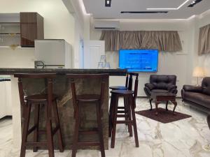 开罗Ideal studio is private villa in 5th settelment in New Cairo的客厅里的酒吧,带两个凳子