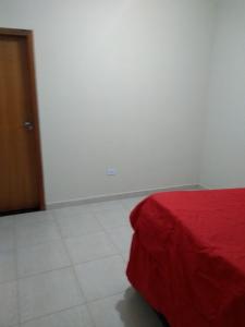 瓜鲁柳斯casa na praia Itanhaém的卧室配有红色的床和白色瓷砖地板。