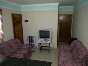 瓜鲁柳斯casa na praia Itanhaém的客厅配有两张沙发和一台电视机
