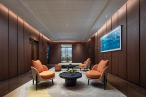 增城广州新塘希尔顿欢朋酒店的一间备有橙色椅子和桌子的等候室