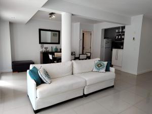 埃斯特角城Green Park Punta del Este的一间带白色沙发的客厅和一间厨房