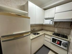卡庞达卡诺阿Apto super luxo beira mar Capão da Canoa的白色的厨房配有水槽和冰箱