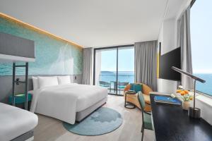 岘港voco Ma Belle Danang, an IHG Hotel的酒店客房设有一张床和一个大窗户