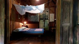清道Traditional Lanna house near hot spring的小卧室配有一张带顶部蚊帐的床