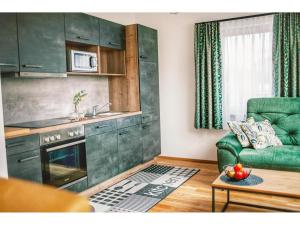 上陶恩Apartment in Hohentauern with sauna的一间带绿色沙发的客厅和一间厨房