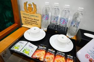 胡志明市Vivian Airport Hotel Saigon的桌子上放有盘子和瓶装水