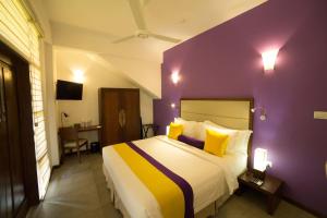 贾夫纳The Thinnai - All-Suites Boutique Hotel的一间卧室配有一张大床和紫色墙壁