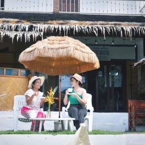 高兰Tiki Bar-KanTiang Guesthouse的两名妇女坐在椅子上,被伞保护