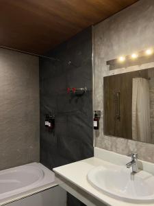 拉差汶里茵拉亚拉查布里旅馆的一间带水槽、浴缸和镜子的浴室
