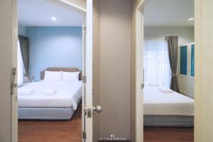 邦盛Bangsaen Heritage Hotel - SHA Plus Certified的一间卧室设有两张床,一扇门通往房间