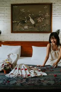乌布扎缇3小屋及温泉酒店的坐在床上的女人,带着一堆毛巾