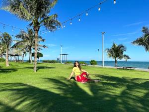 隆海Oceanami Villa Long Hải - Vũng Tàu的坐在海滩附近草地上的女人