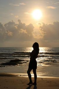 隆海Oceanami Villa Long Hải - Vũng Tàu的日落时站在海滩上的女人