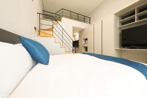 丽水市Coopstay Yeosu Hotel的一间卧室配有一张带蓝色枕头的床,并设有一个楼梯