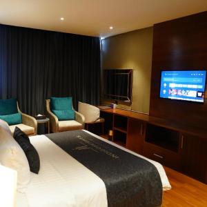 拉合尔Indigo Heights Hotel & Suites的配有一张床和一台平面电视的酒店客房