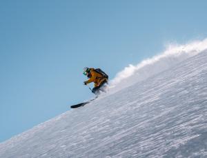 伦策海德Revier Mountain Lodge Lenzerheide的一个人在雪覆盖的斜坡上滑板