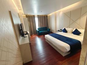 穆扎夫法尔普尔The Emerald Hotel & Siya Milan Banquets的配有一张床和一把椅子的酒店客房