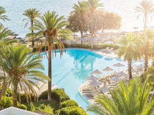 科斯镇Grecotel Kos Imperial的享有游泳池的顶部景色,游泳池拥有棕榈树和遮阳伞
