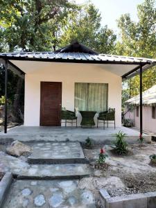 达兰萨拉Dev Bhoomi Farms & Cottages的一个小房子,设有门廊和两把椅子