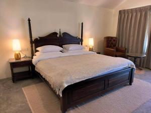 达兰萨拉Dev Bhoomi Farms & Cottages的一间卧室配有一张大床、两盏灯和一把椅子