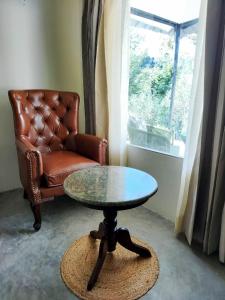 达兰萨拉Dev Bhoomi Farms & Cottages的窗户房间里一张桌子和一把椅子