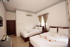 潘切Nu Cuoi Mui Ne Hotel & Restaurant的酒店客房,配有两张带鲜花的床