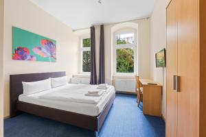 柏林康米纽斯酒店的一间卧室配有一张床、一张书桌和两个窗户。
