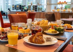 阿尔梅勒Best Western Plus Plaza Almere的餐桌,带食物盘和橙汁杯