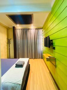 TumpatSuza Hostel的一间带绿色墙壁的卧室、一张床和电视