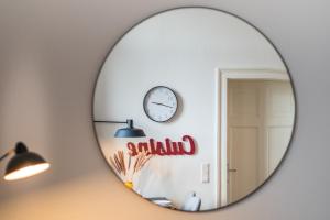 圣英贝特SCHWARZLINS LoftRaum - Stilvolles Apartment mit Smart TV, NETFLIX, Disney Plus, schnellem WLAN, Parken, Nespresso的墙上挂着时钟的镜子