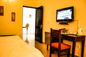PadmiVan Durga Villas & Suites的一间卧室配有一张床和一张书桌及电视