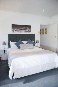 SandtonLonehill - Deluxe Garden Cottage 2的卧室配有带蓝色枕头的大型白色床