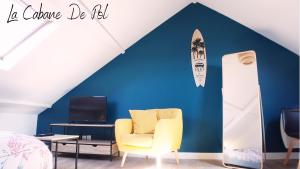 敦刻尔克La Cabane De Pol的一间设有黄色椅子的房间,一个冲浪板在蓝色的墙上