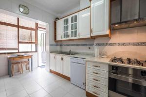 奥迪韦拉什Apart Lisboa confortavel 2 quartos com terraço的厨房配有白色橱柜和炉灶烤箱。