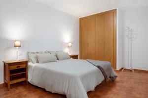 法马拉Casa Famara的卧室配有白色的床和木制橱柜。