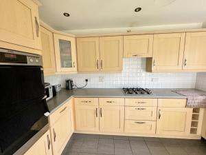 贝辛斯托克Elvetham Nest Guesthouse, Basingstoke的厨房配有木制橱柜和炉灶烤箱。