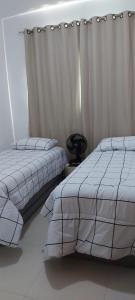 卡皮托利乌Apartamento Aconchegante的一间卧室配有两张床和窗帘