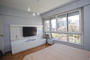 布宜诺斯艾利斯Stylish 3 BR Family Apt in Palermo的一间白色客房,配有电视和两个窗户。