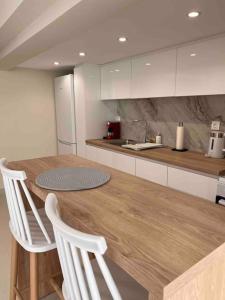 米蒂利尼Minimal Cozy Apartment的厨房配有木桌和白色橱柜。