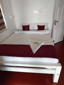 阿勒皮Tripsea Beach Villa的卧室内的白色床和红色枕头