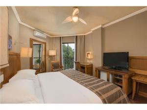 格拉玛多Wish Serrano Resort的配有一张床和一台平面电视的酒店客房