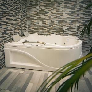 卡利Malik Hotel Boutique的浴室设有白色浴缸,铺着瓷砖。