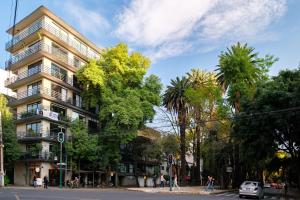 墨西哥城Nido Condesa by RentinBA的一条树木繁茂的城市街道上高大的建筑