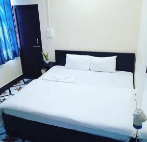 因帕尔OYO Flagship The Thangal Hotel的一间卧室配有一张白色的床和黑色床头板