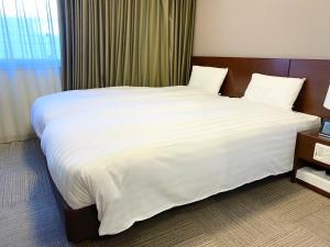 高松多美迎高松酒店的一张大白色的床,位于酒店客房内