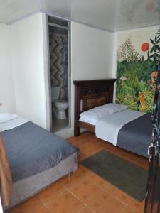 波哥大Hostal Chorro De Quevedo的一间带两张床的卧室和一间带卫生间的浴室