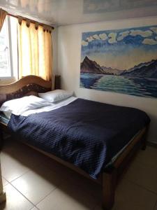 波哥大Hostal Chorro De Quevedo的卧室内的一张床铺,墙上有绘画作品